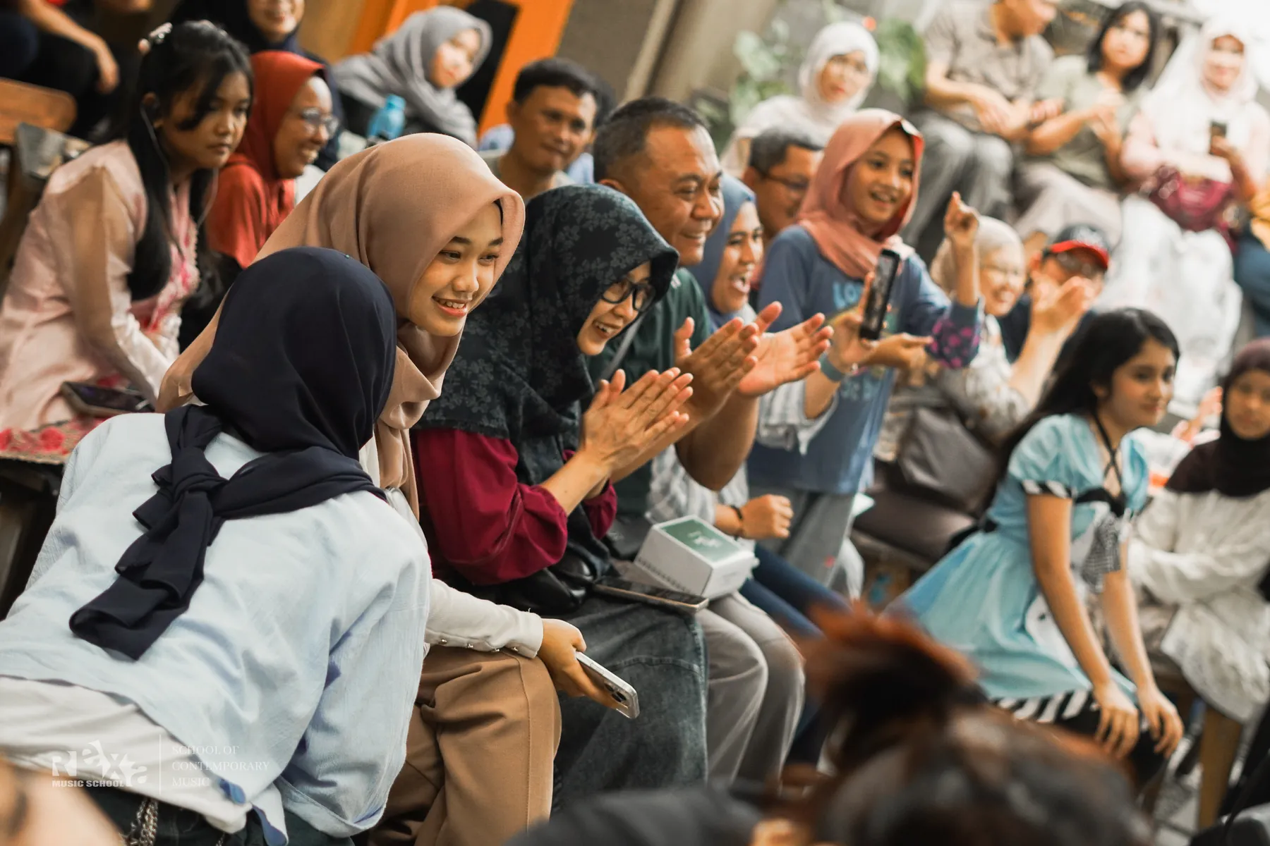 Keluarga bertepuk tangan menonton penampilan murid