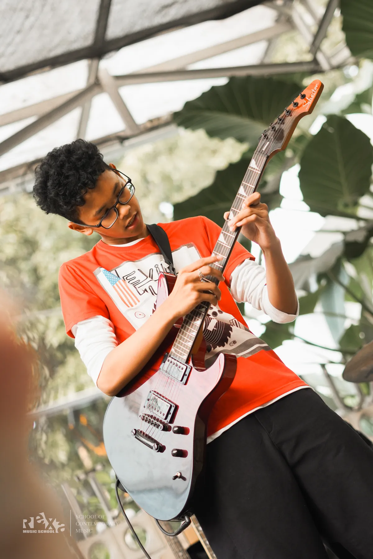 Murid memainkan gitar elektrik dengan kaus oranye